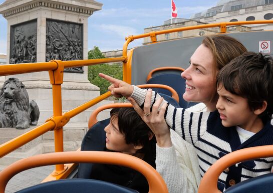 A mother shows her kids the London sights from atop the double decker bus