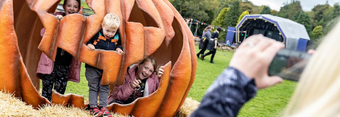 A giant pumpkin with kids inside of it are photographed by a mum