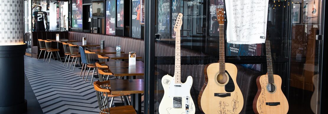 3 guitars and a band's t-shirt are displayed as part of the Wembley Stadium tour