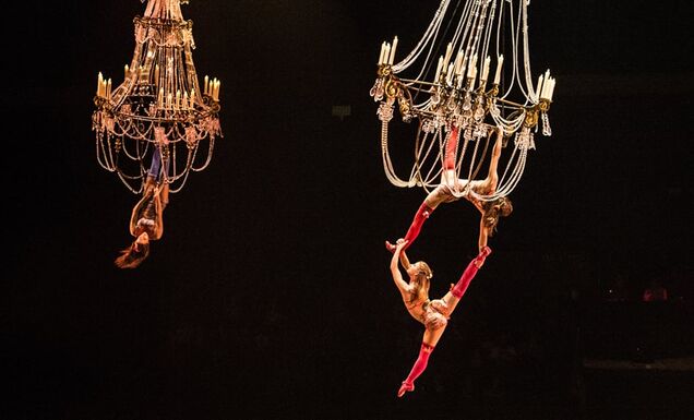 Circus performers of Cirque du Soleil doing an acrobatic stunt from a hanging chandelier