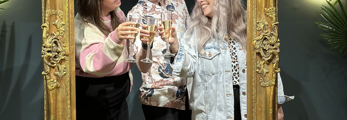 Friends enjoy a photo opportunity with a large gold frame at Madame Tussauds Champagne Bar