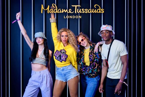 Beyonce at Madame Tussauds along with three young people posing for a photograph