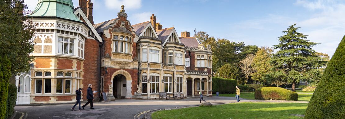 Bletchley Park from the outside with a blue sky and rounded green lawn