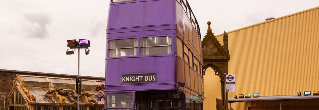 A giant purple double decker bus stands outside Warner Bros Studios