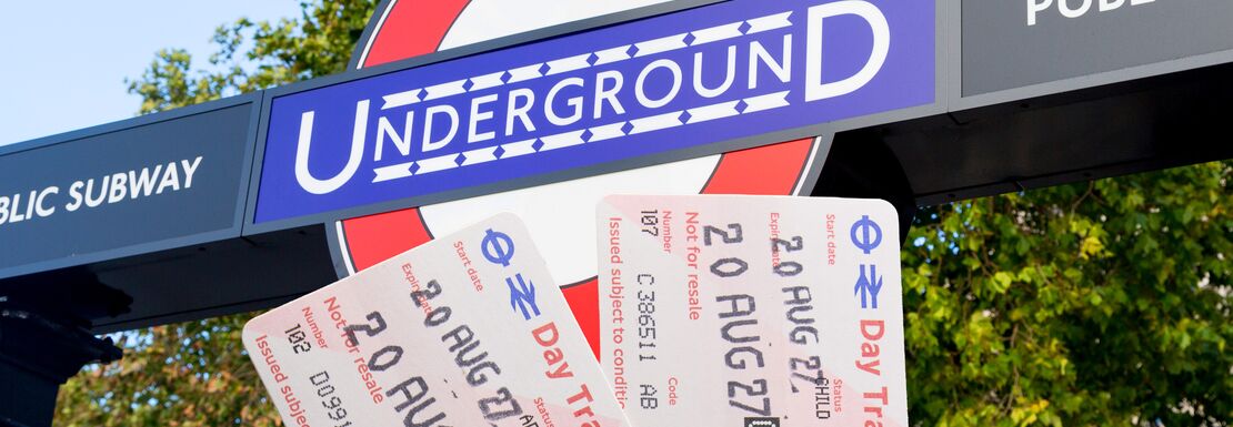 London Day Travelcard being held up outside the entrance to an underground station