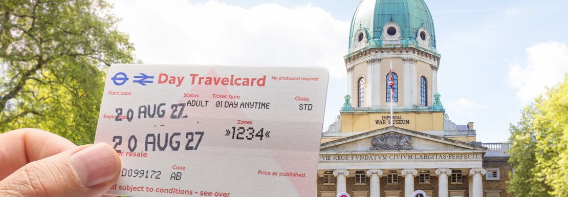 Outside a London museum a hand holds up a London Day Travelcard