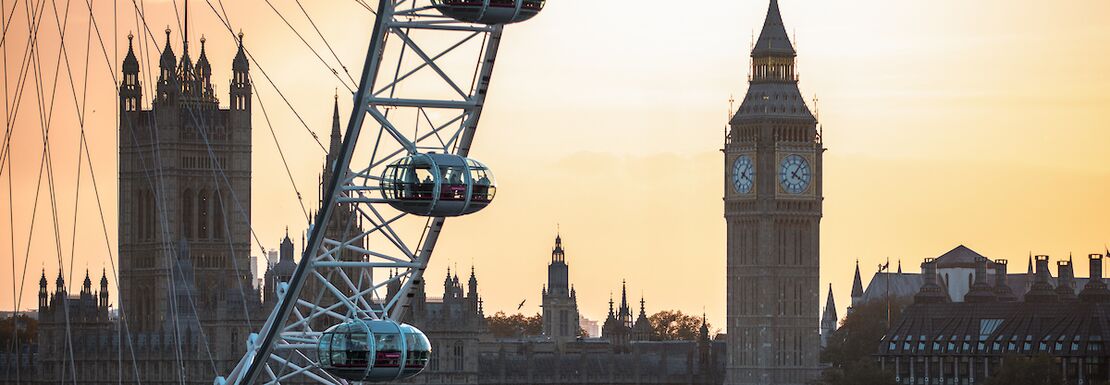 London Eye revolves around a dusky sky with London's House of Commons in the background