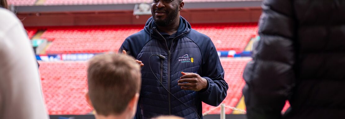 A tour guide showing a group around the pitch at Wembley Stadium