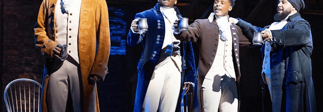 A group of actors raising their tankards on stage in Hamilton