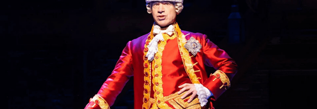 An actor playing King George III stands centre-stage in Hamilton