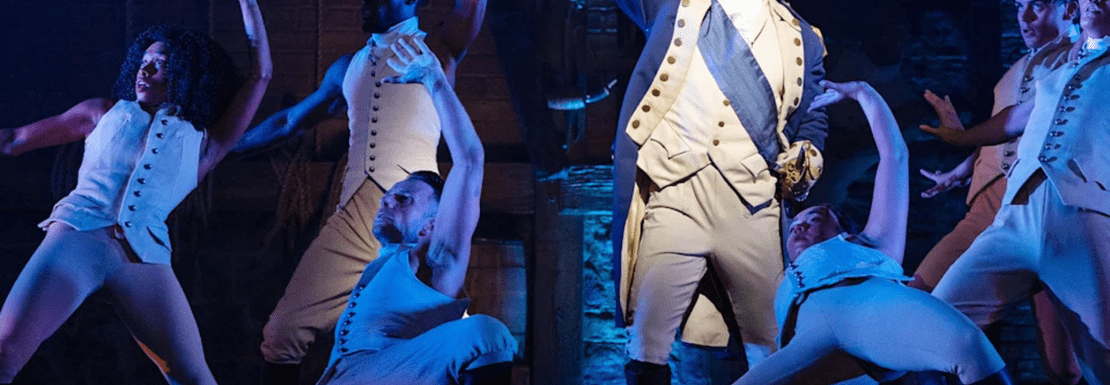 An actor playing George Washington on stage surrounded by dancers in Hamilton