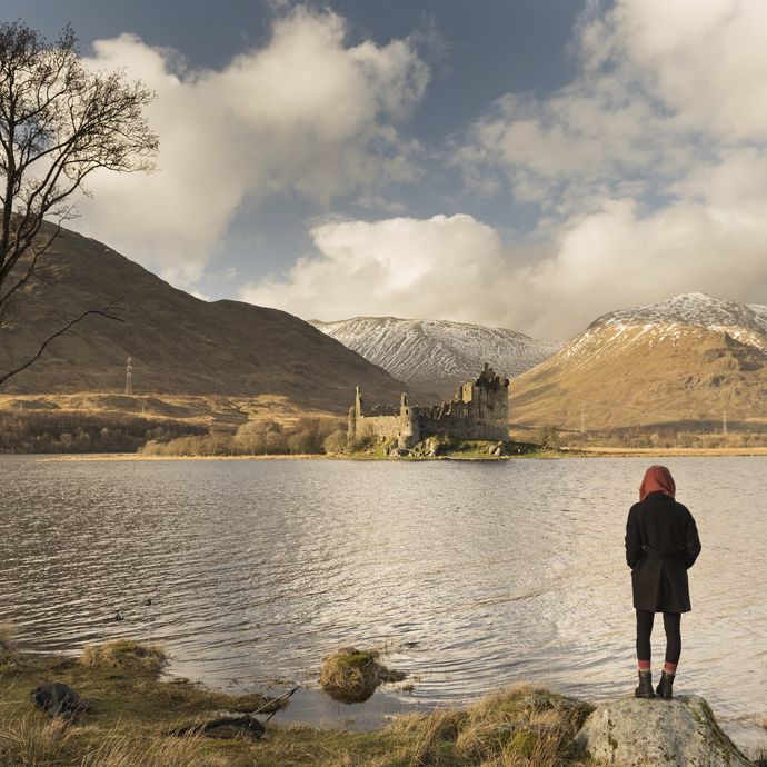 Girl standing on rock with view of castle in distance