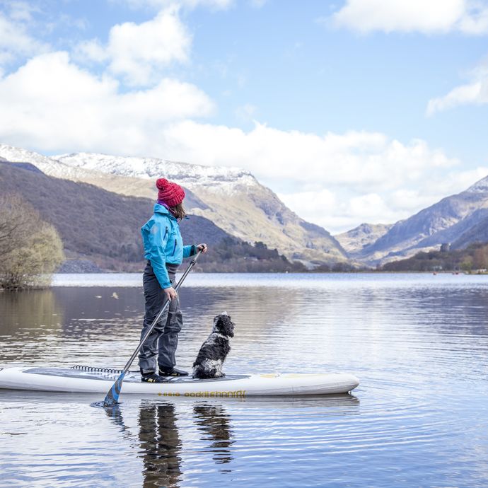 Woman and dog on a paddle-board on lake near mountains
