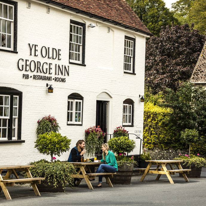 A couple sitting outside the pub on a bench having a drink