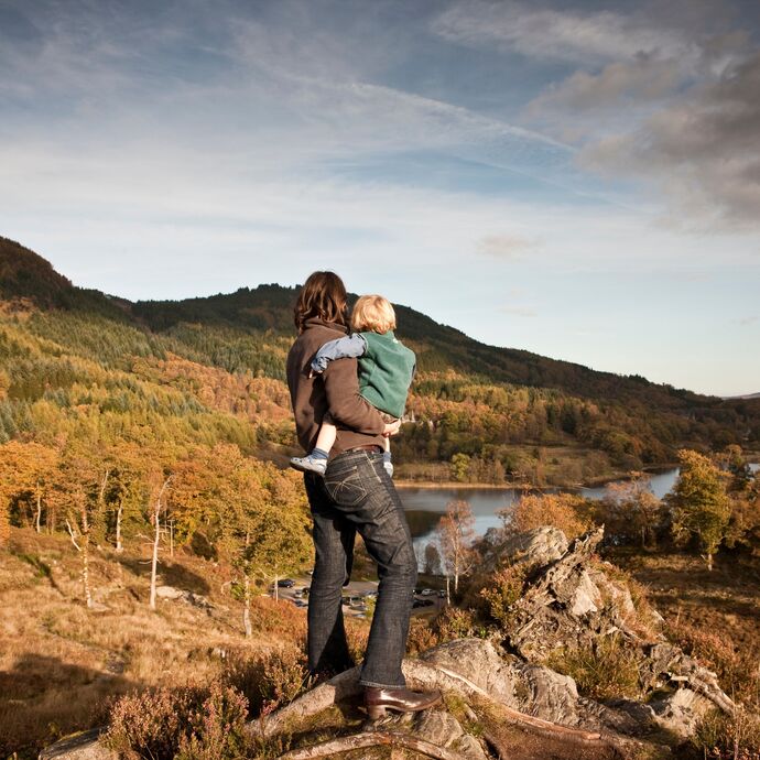Woman and child standing on a hilltop overlooking a lake