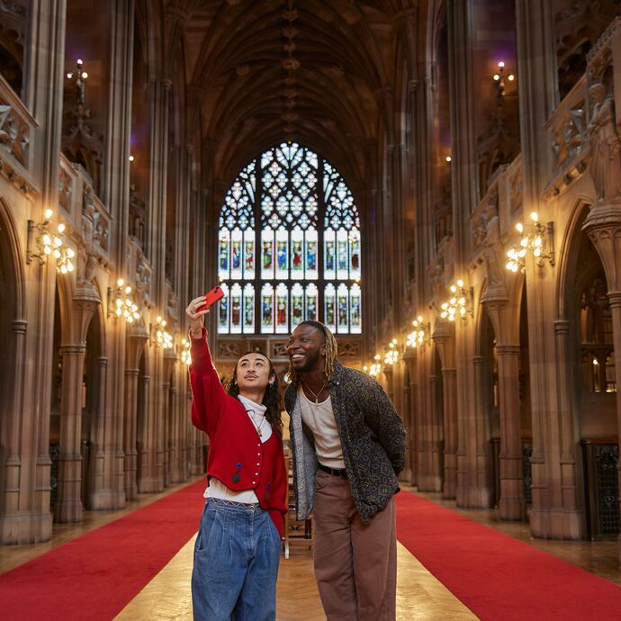 Two people walking through a dramatically lit library in Manchester