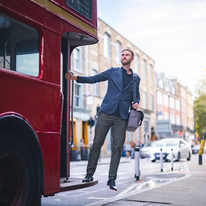 A man stands at the end of a red bus in London
